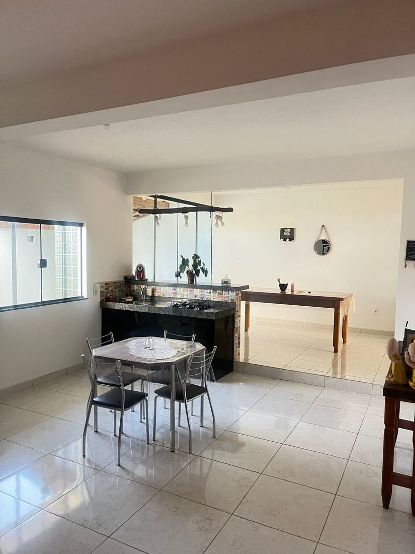 Cozinha com bancada e mesa de jantar, aberta para outro ambiente