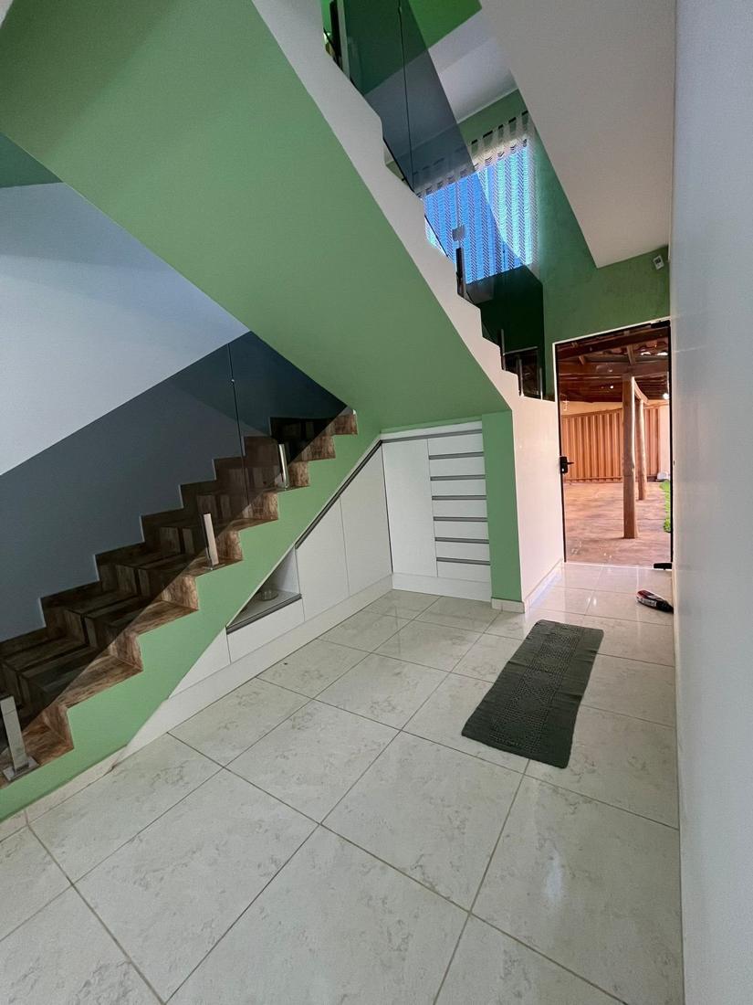 Hall de entrada com escada de guarda-corpo de vidro e armários planejados